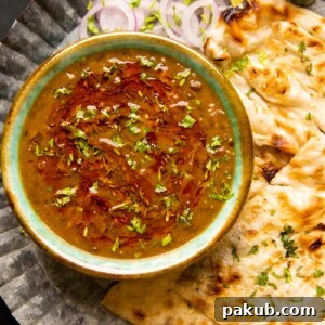 Langar wali dal served in a green ceramic bowl with naan and onions on the side