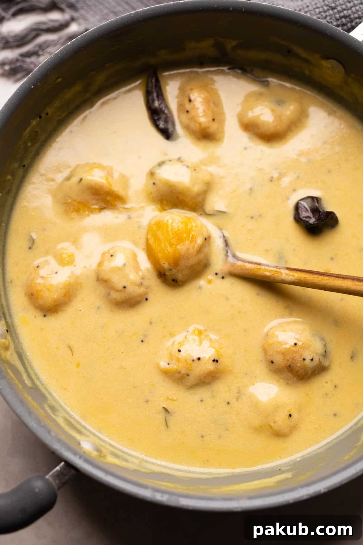 Mango Kadhi simmering in a traditional Indian kadai, with a ladle resting nearby, ready to be served.