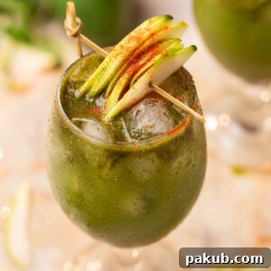 aam panna served in a glass and garnished with raw mango slices and chilli powder