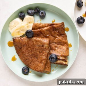 Banana Dosa served on a green kids plate with bananas, honey and blueberries on the side