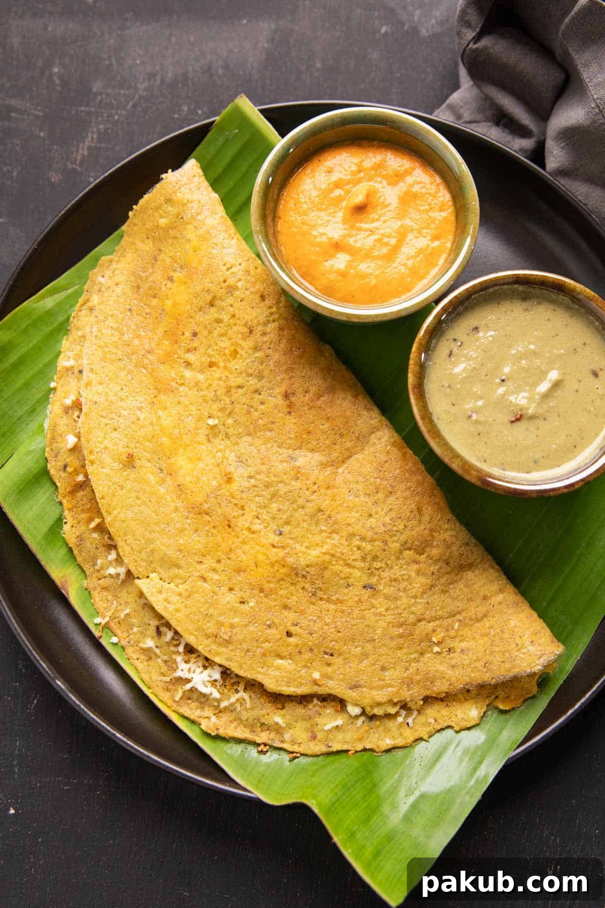 High Protein Dosa served on a banana leaf with vibrant chutneys and a rich curry on the side, highlighting its delicious and nutritious appeal.