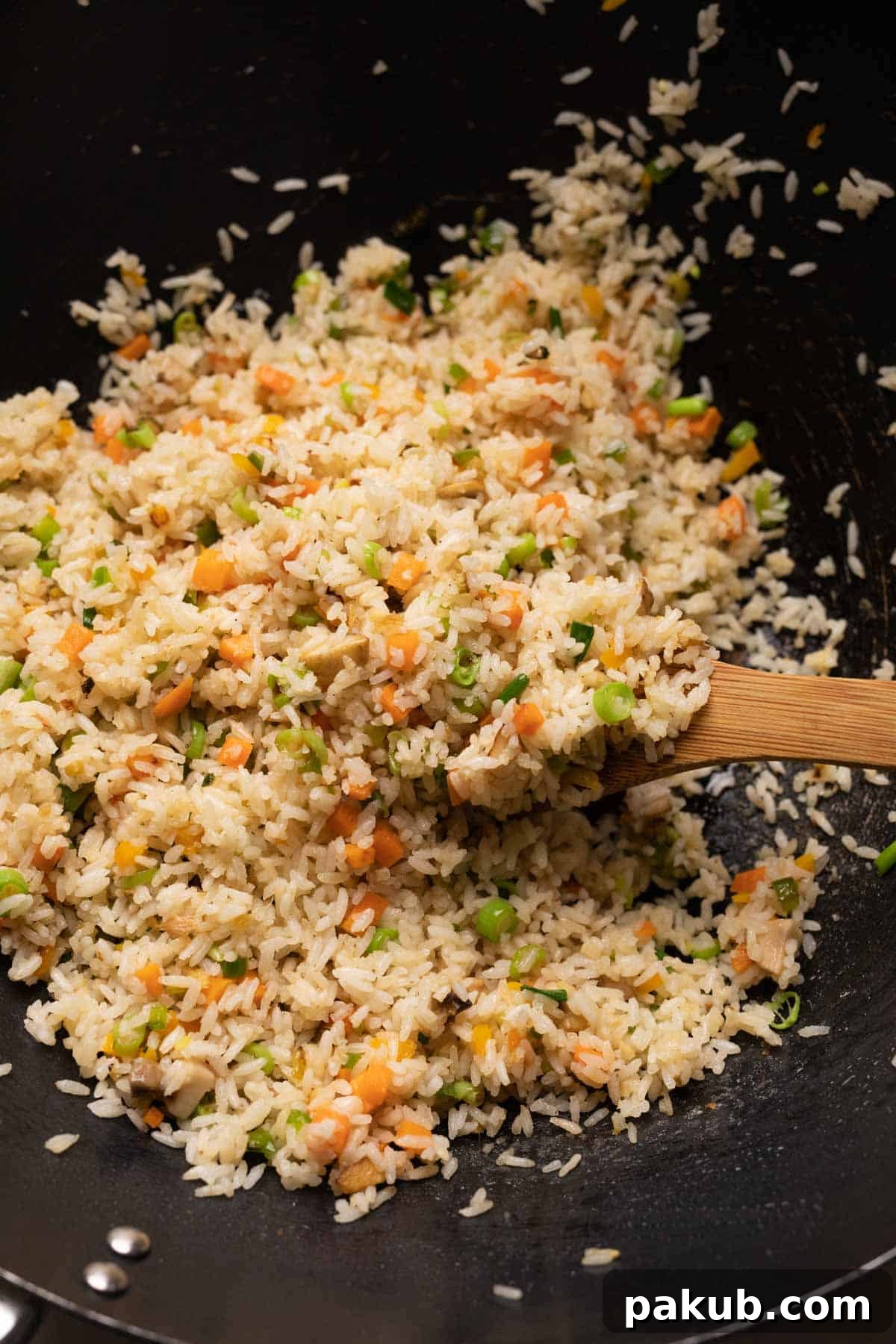 A close-up shot of freshly made vegetable fried rice being stir-fried in a large, hot wok, highlighting the vibrant colors and steam.