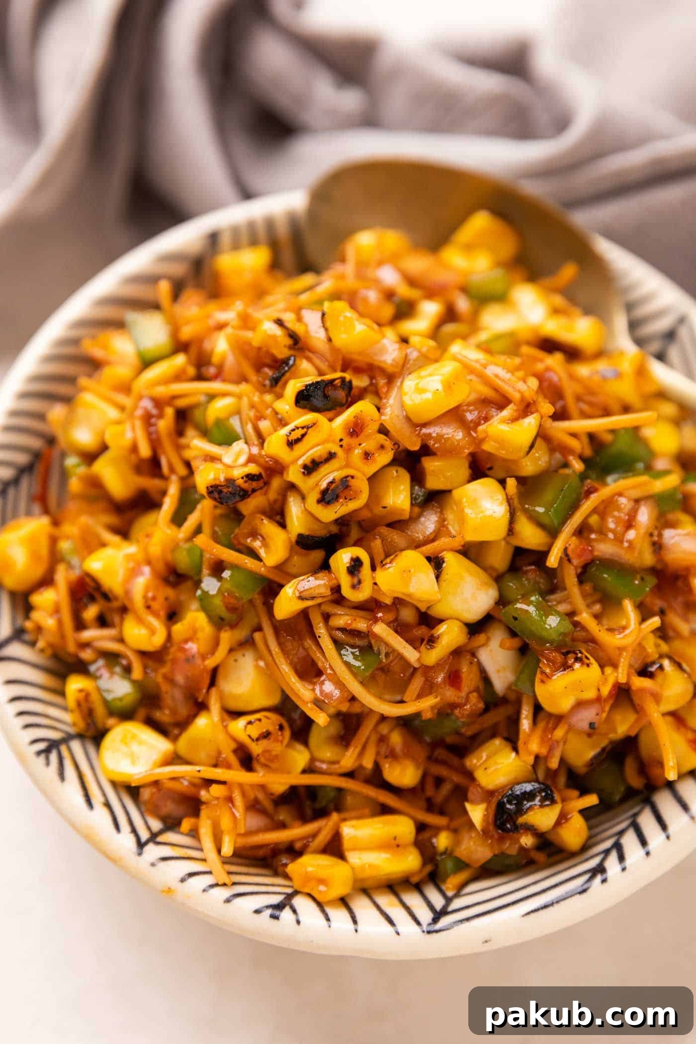 Sweet Corn Chaat 2 A vibrant bowl of Chinese-Style Corn Bhel, garnished with fresh herbs and served with a spoon, highlighting its crunchy texture.