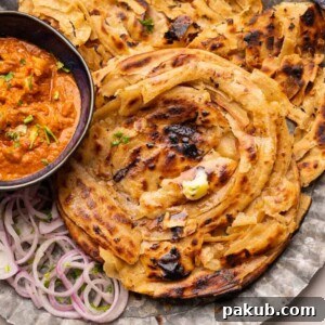 Lachha Parathas served on a plate with curry and onions