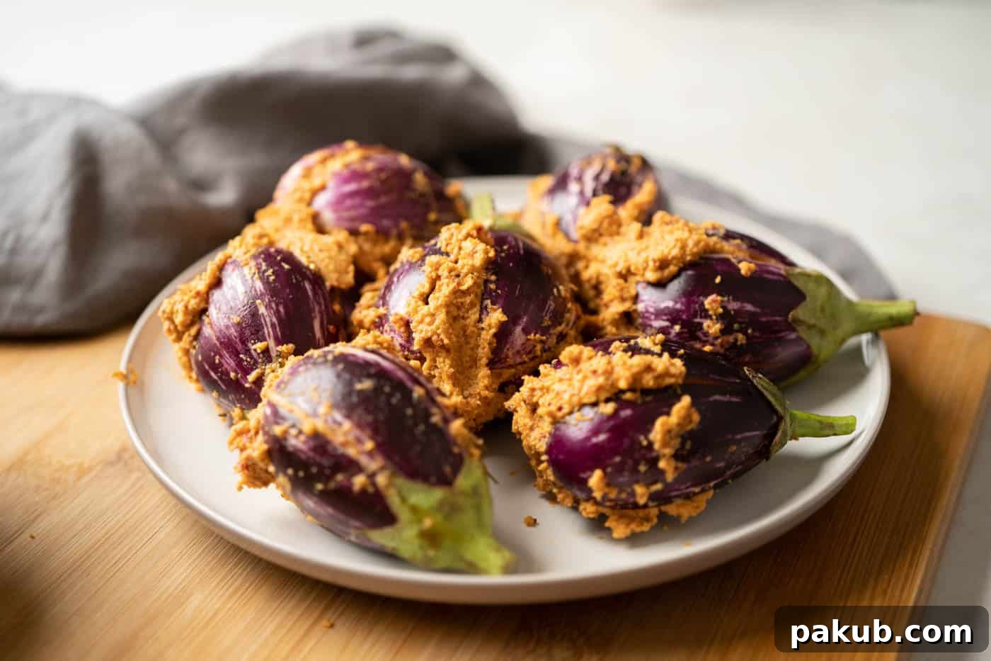 Picture of small, purple-striped brinjals on a plate, meticulously stuffed with the aromatic masala paste, ready to be cooked.
