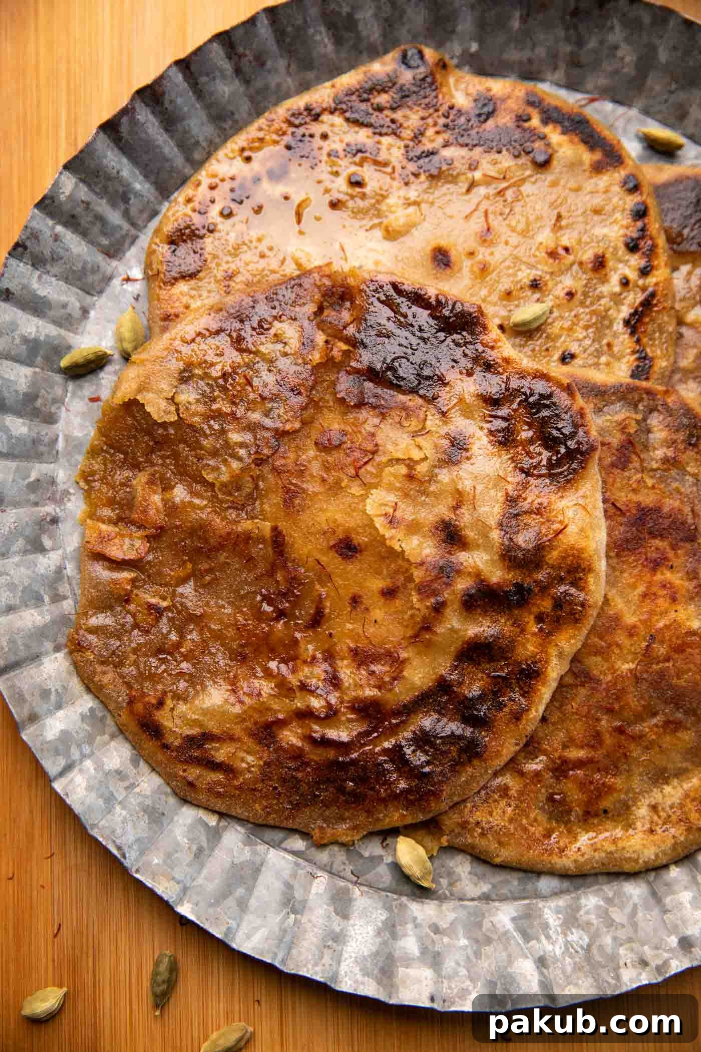 Indian Sweet Lentil Flatbread 2 Puran polis served on a silver platter drizzled with saffron and ghee