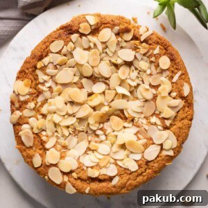 A slice of Mawa Cake served on an elegant white platter, accompanied by a side of thinly sliced almonds, highlighting its rich and inviting texture.