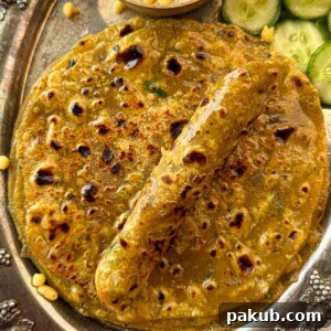 Closeup of dal parathas piled on top of each other, with one rolled up, showing a golden texture