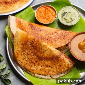 Freshly made dosas served on a banana leaf platter with accompaniments like sambar and chutney