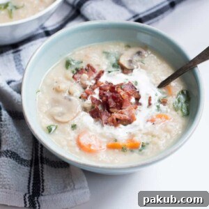 A hearty bowl of Homestyle Barley Chicken Fall Soup, garnished with crispy bacon and a swirl of cream.