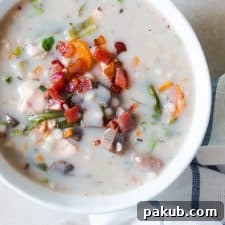 Creamy Slow Cooker Chicken Barley Soup, topped with savory fried bacon and served in a classic white bowl.