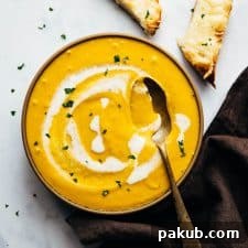 Creamy roasted pumpkin soup served in a rustic bowl with cheesy bread for dipping.