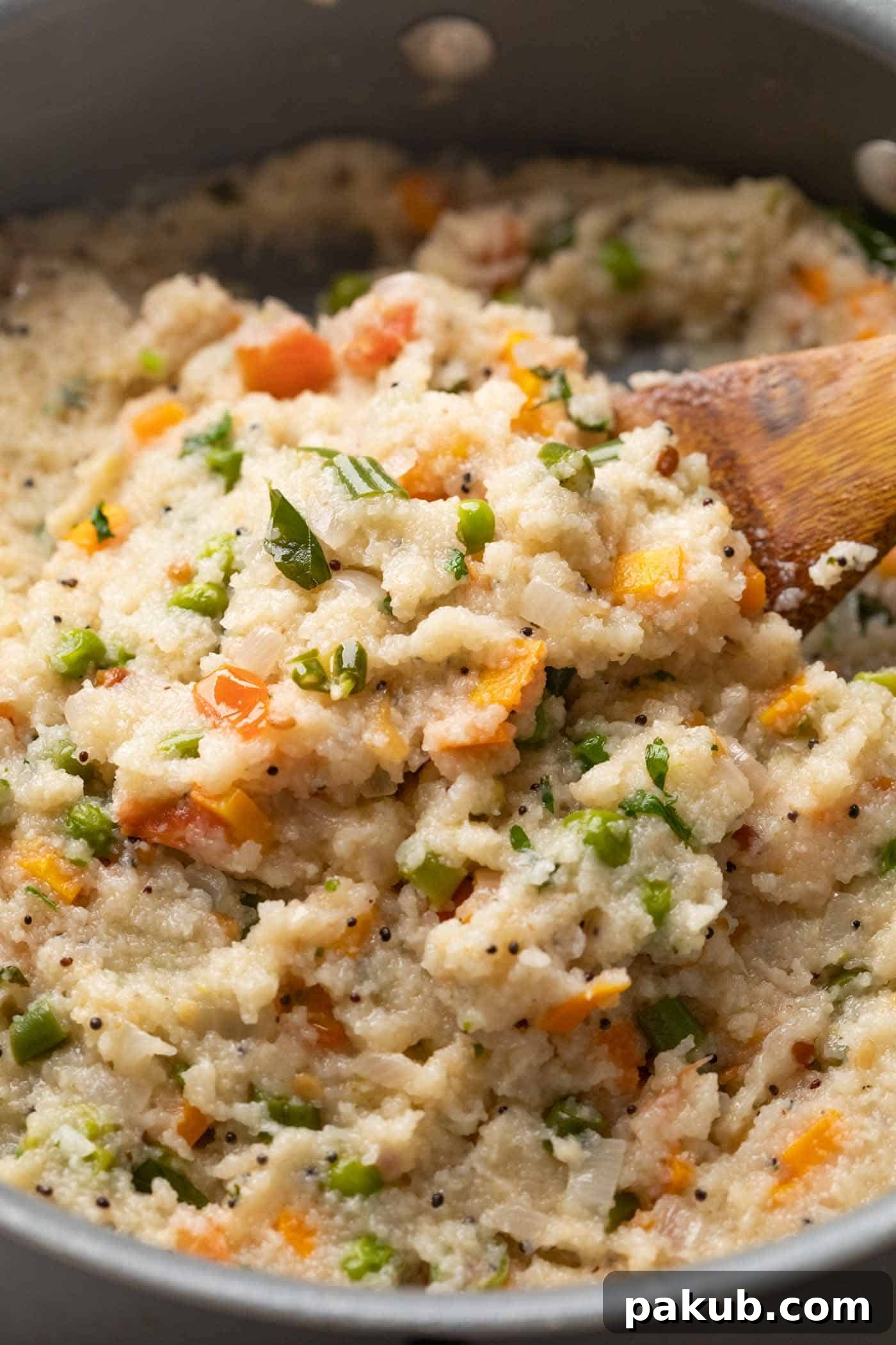 Vibrant Vegetable Semolina Upma 6 A close-up view of freshly cooked, soft, and fluffy Vegetable Upma still in the pan, highlighting its texture and the vibrant mix of vegetables, ready to be served.