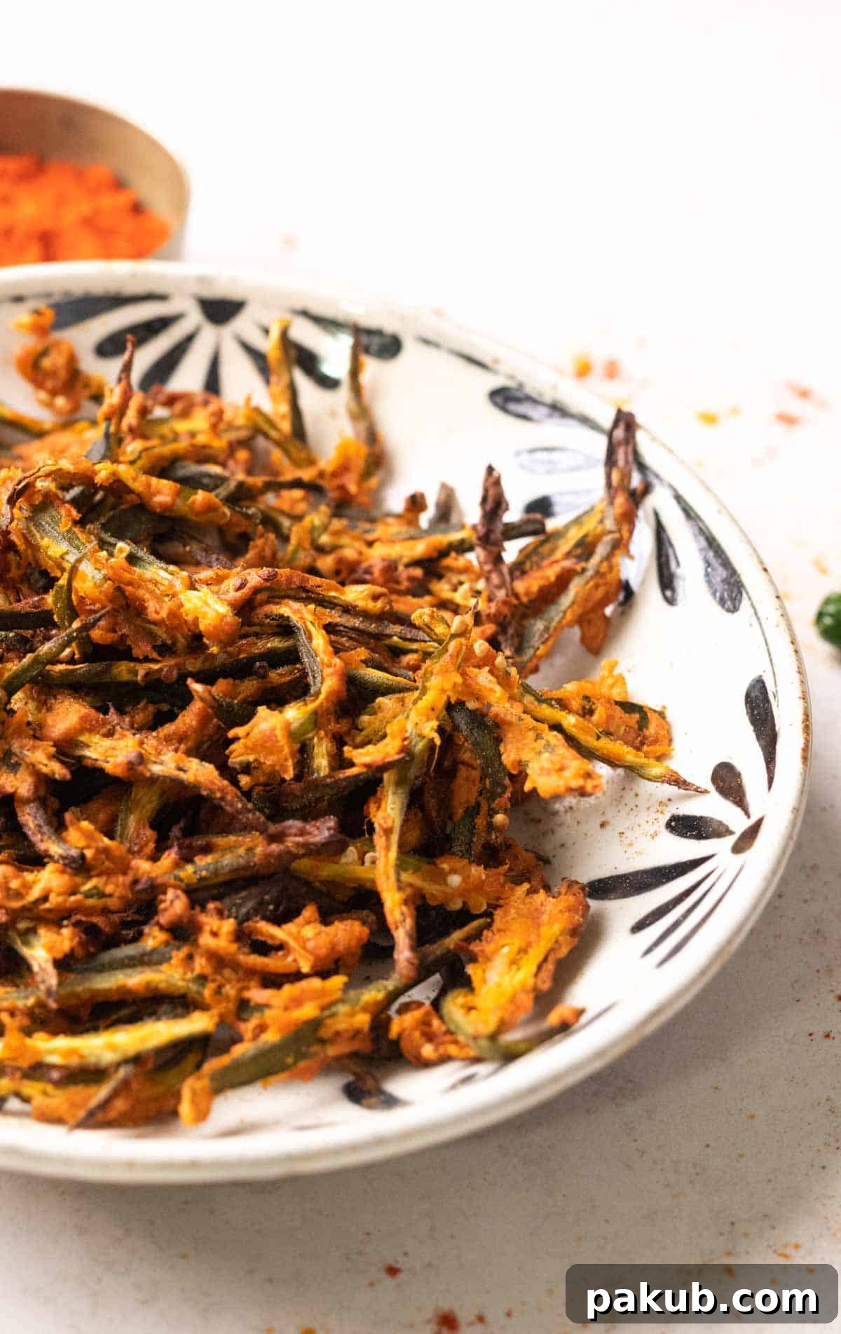 Crispy Air Fryer Okra 7 A vibrant, close-up shot of crispy air fried kurkuri bhindi in a white bowl, ready to be enjoyed.