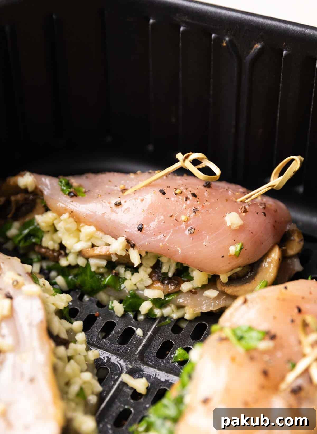 Golden Air Fryer Stuffed Chicken Breasts 2 Two golden-brown stuffed chicken breasts resting in an air fryer basket, ready to be served.