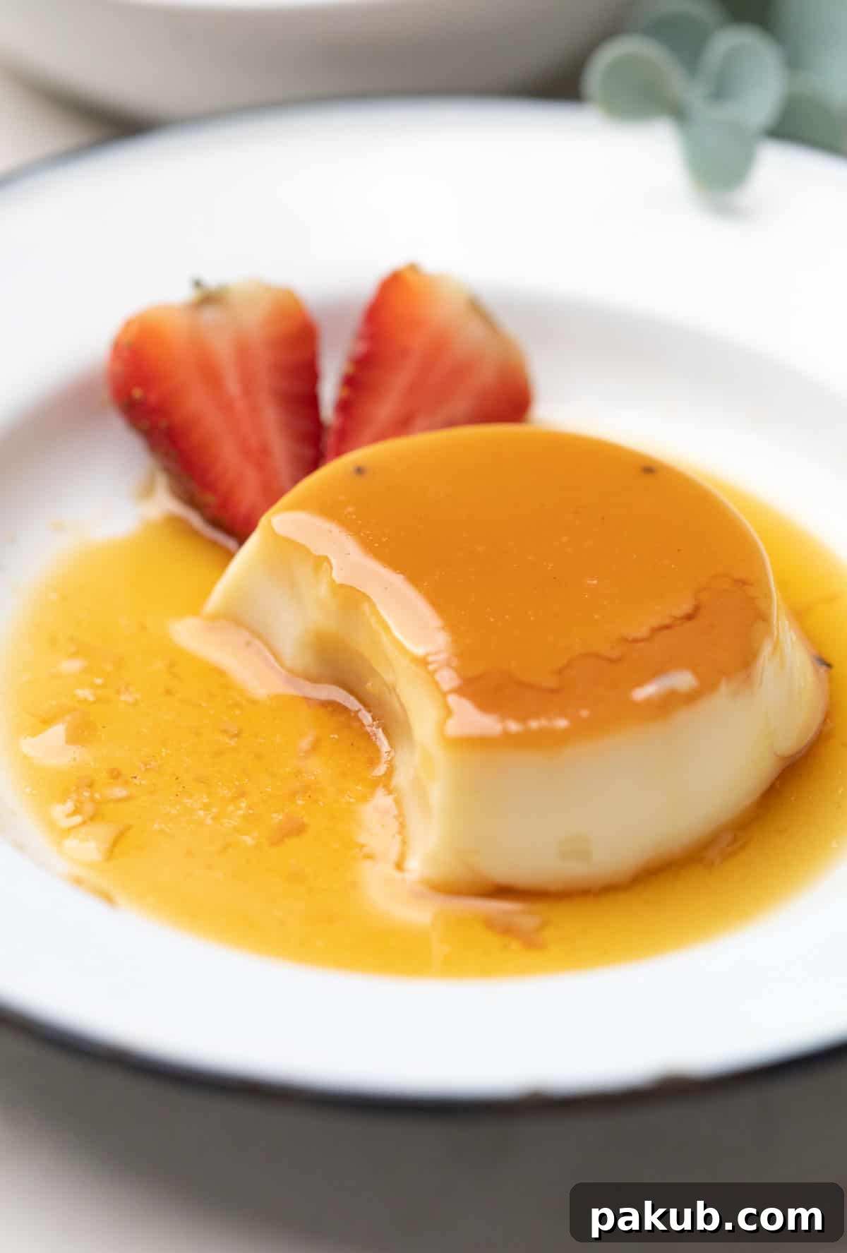 Luscious Caramel Flan 2 A perfectly demoulded caramel custard, served on a pristine white plate, garnished with vibrant fresh strawberries on the side, showcasing its golden caramel layer and smooth texture.