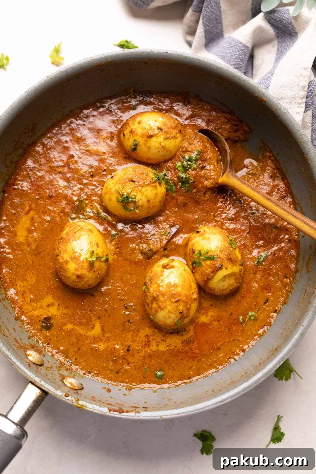 Classic Dhaba Egg Curry 8 A close-up shot of Dhaba Style Egg Curry simmering in a grey cast iron pan, showing the thick, rich gravy and perfectly coated eggs, ready to be served.
