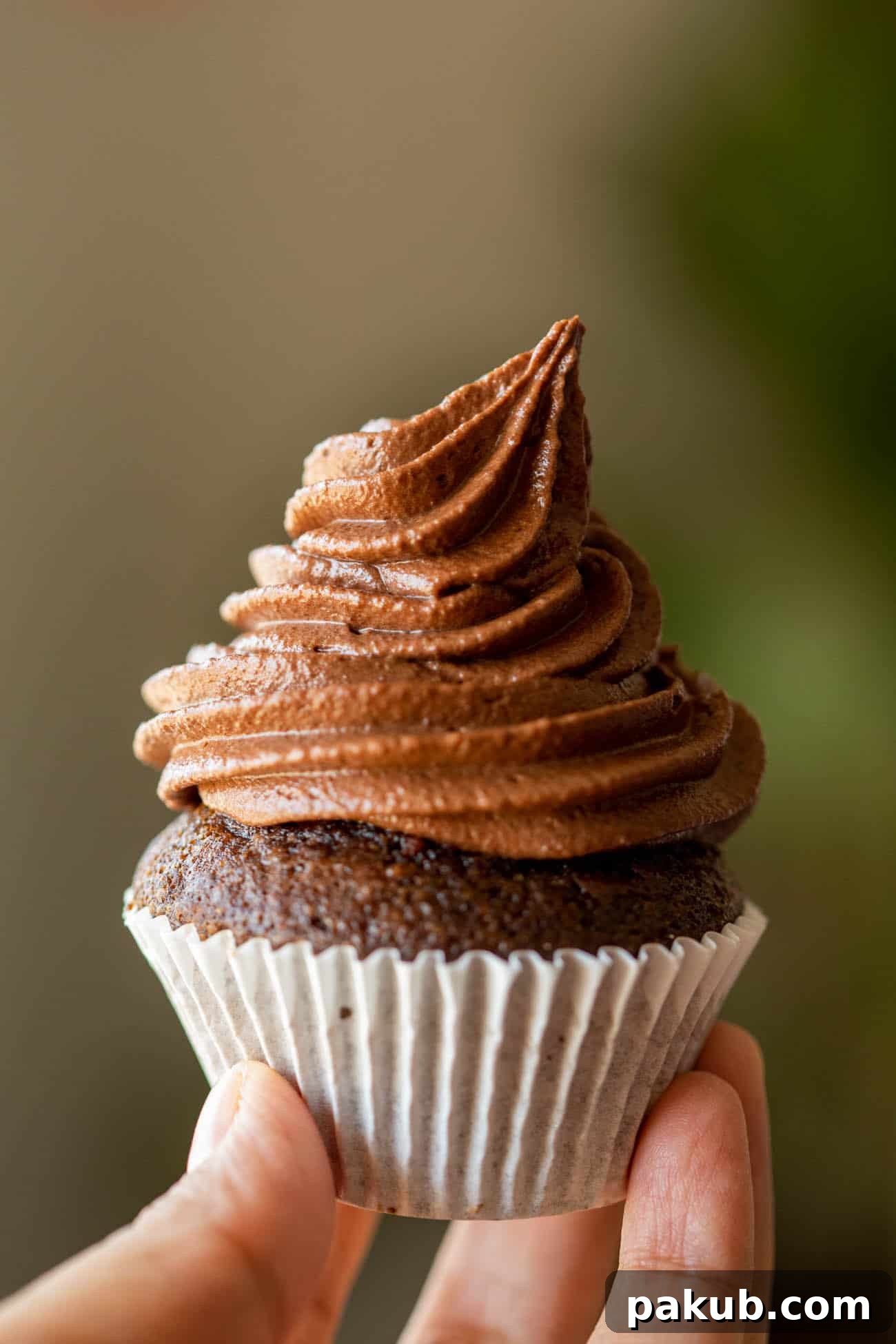 Close-up of a chocolate cupcake adorned with a perfectly piped swirl of chocolate buttercream, ready to be enjoyed.