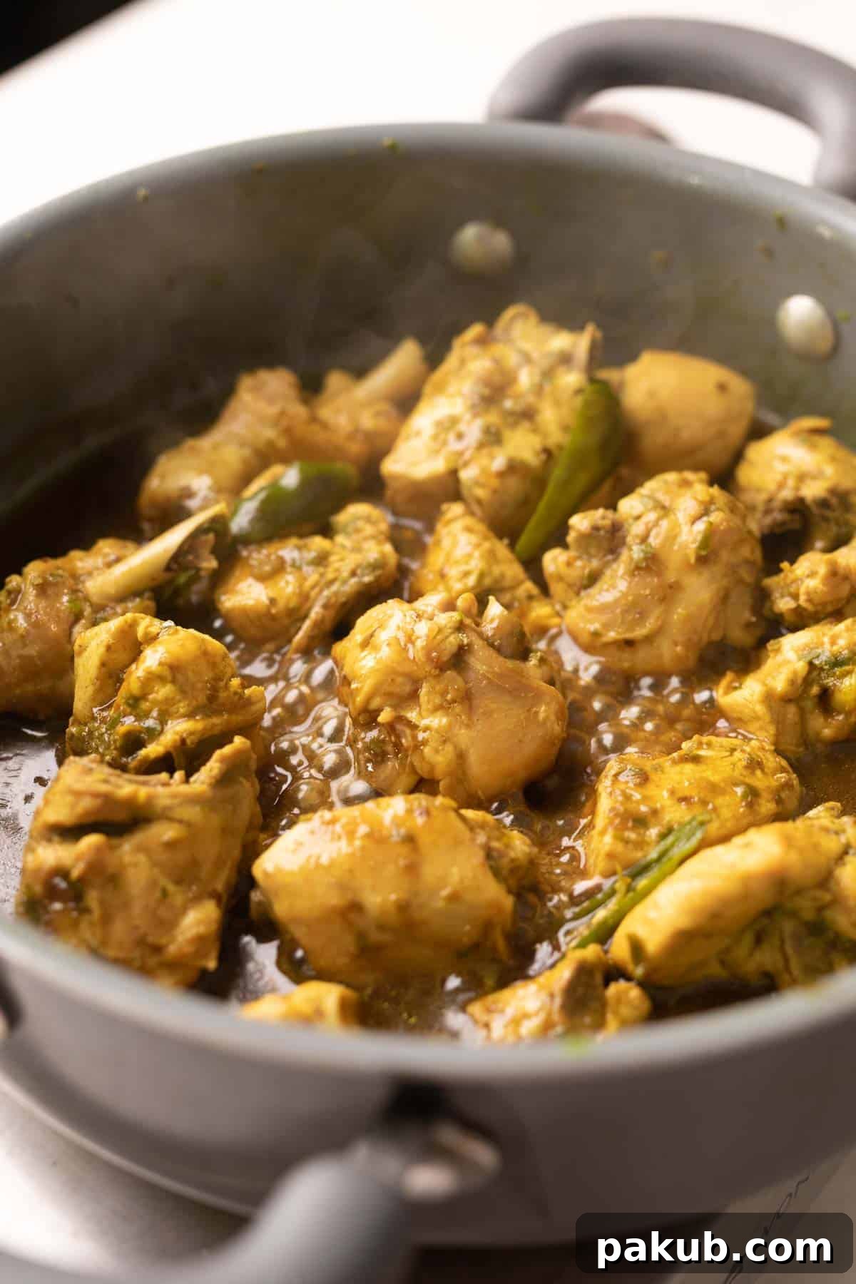 Close-up shot of Andhra Chilli Chicken simmering in a traditional cast iron kadai, steam gently rising, ready to be served.