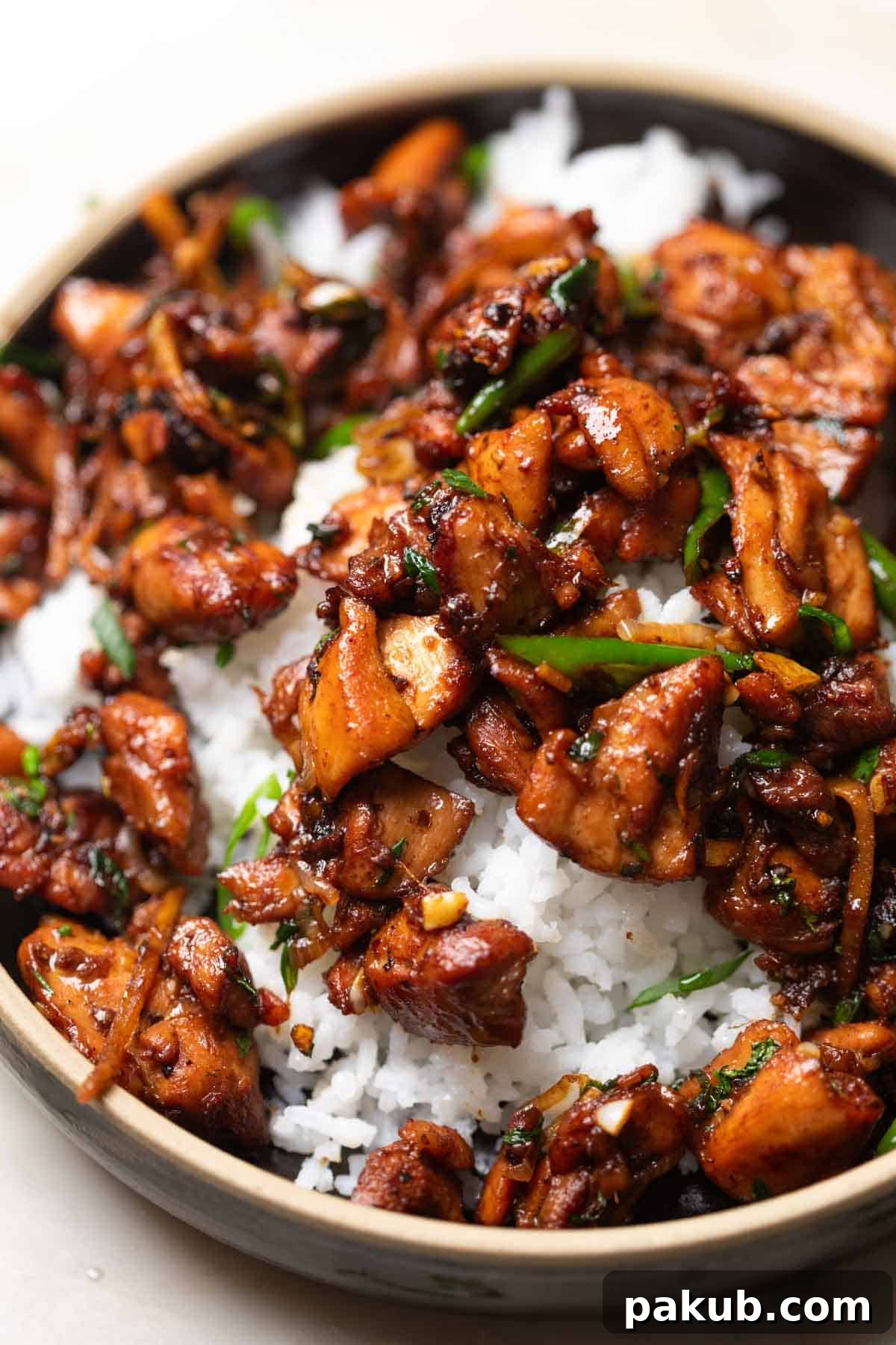 A close-up view of the ginger chicken stir fry, beautifully plated over fluffy white rice in a bowl, highlighting its glossy sauce and tender pieces.