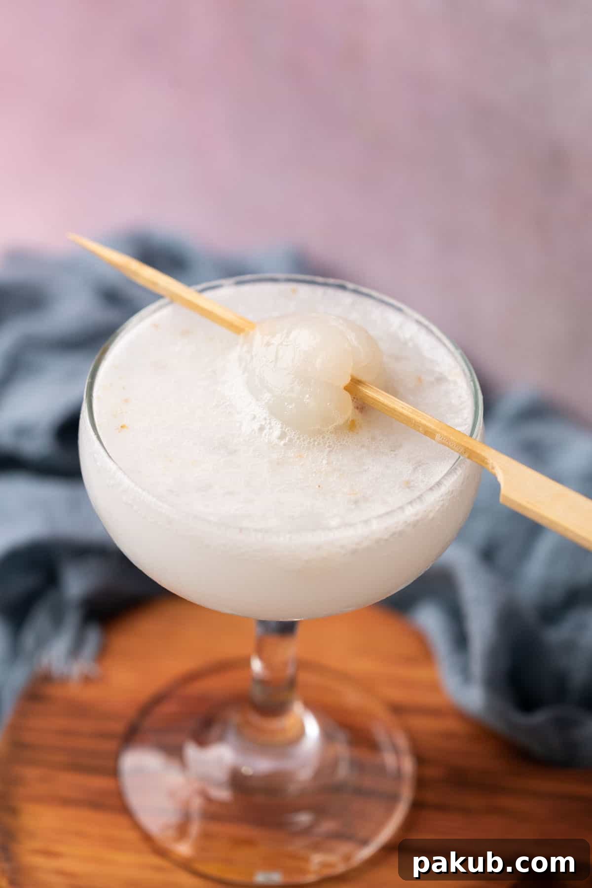 A refreshing glass of Lychee Soda, topped with a fresh lychee on a toothpick, ready to be enjoyed on a hot day.