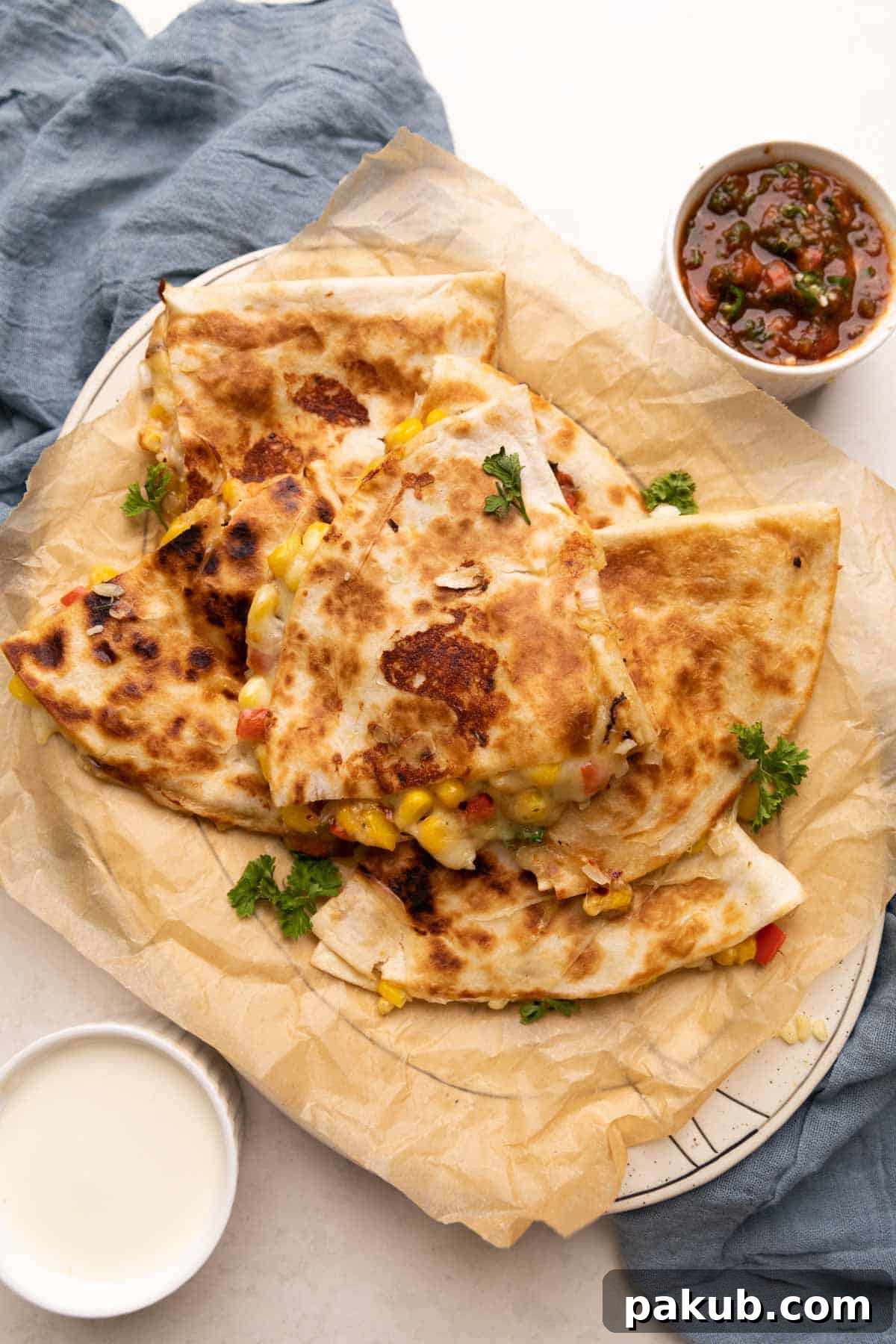 A close-up shot of a perfectly cooked bell pepper, corn, and cheese quesadilla, cut into triangles and stacked, revealing the rich melted cheese and colorful vegetable filling, garnished with fresh cilantro and served with salsa.