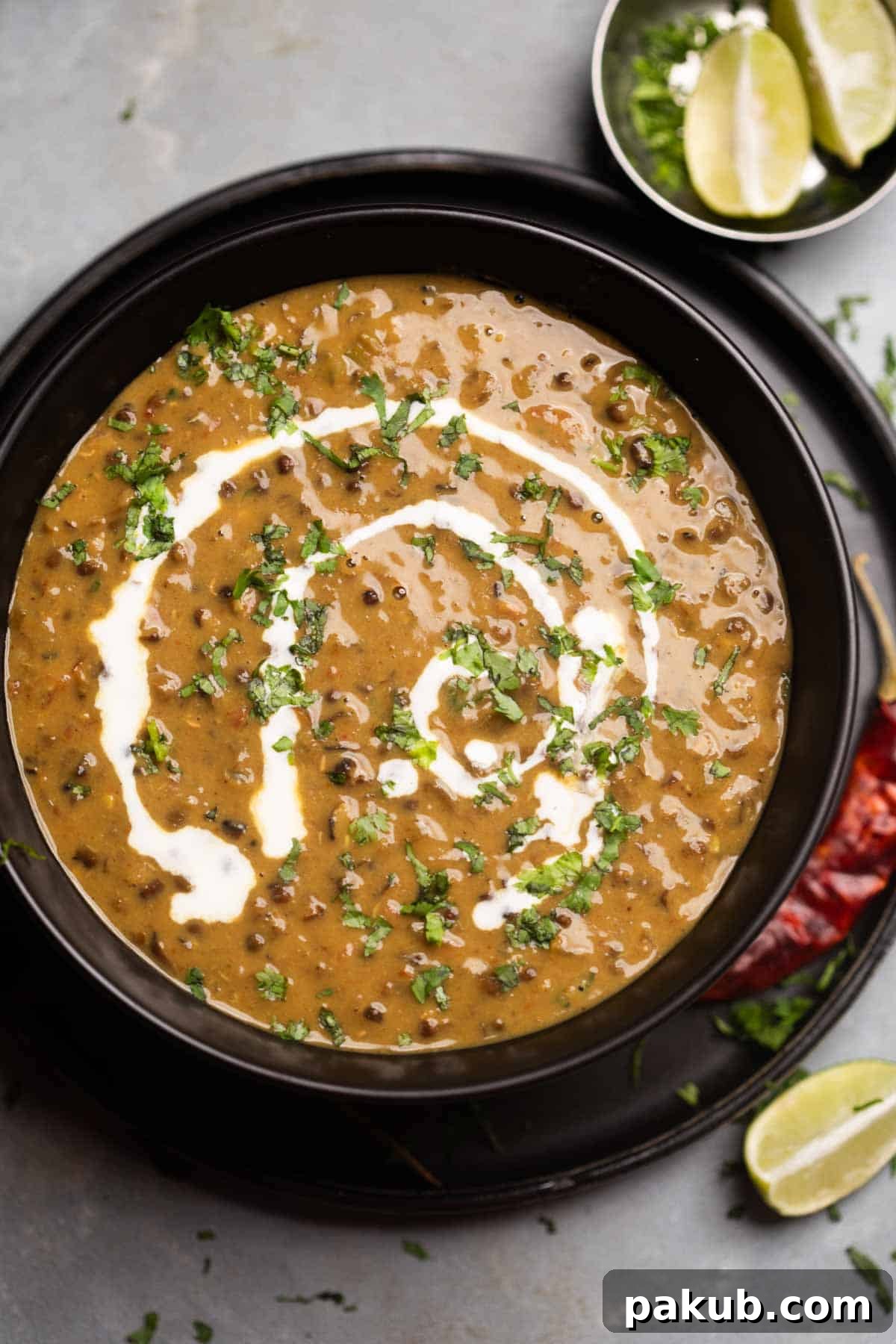Amritsar's Signature Dal 5 Amritsari dal drizzled with cream and coriander in a black bowl