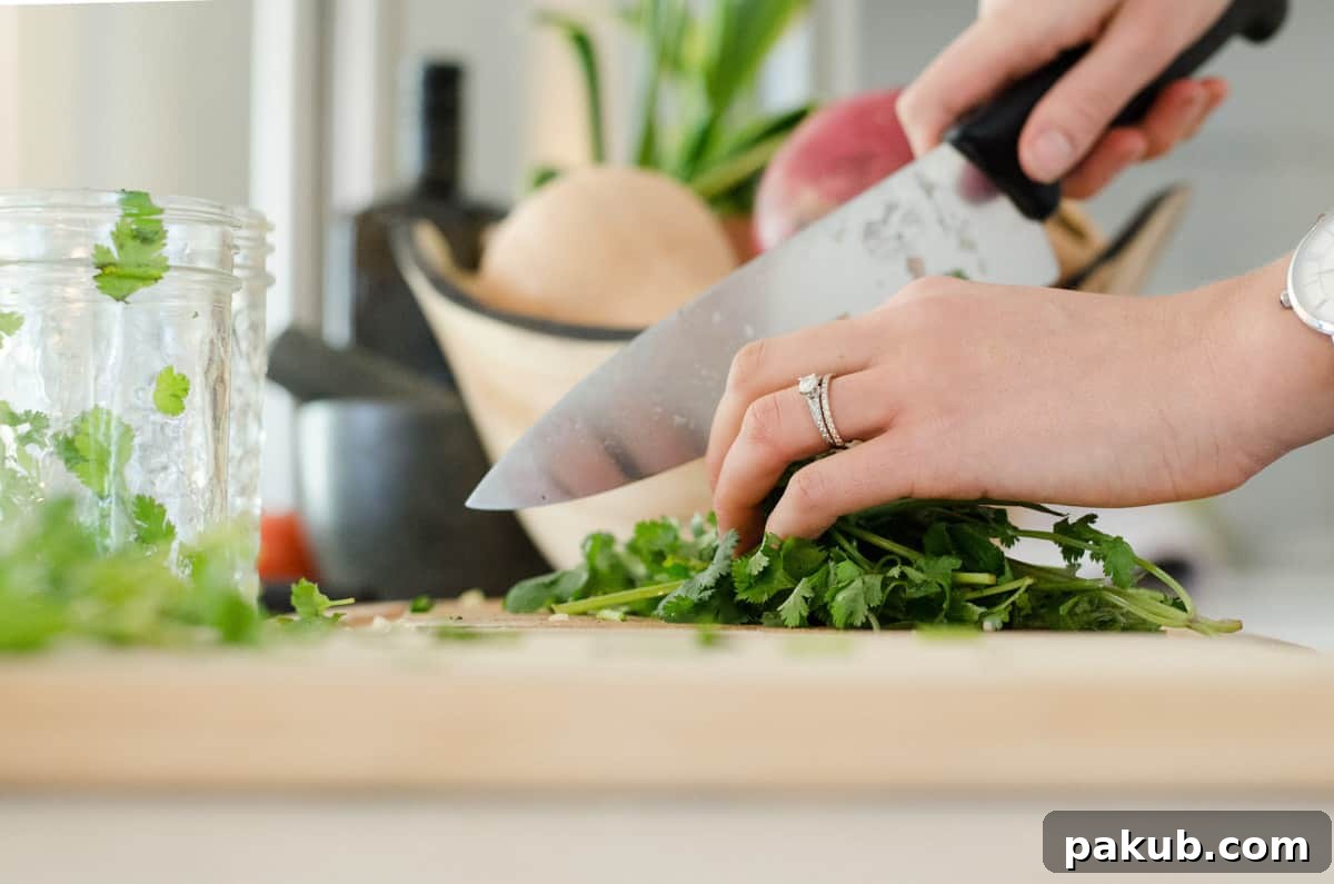 Close-up shot of fresh herbs, possibly parsley and rosemary, being prepared on a wooden chopping board.