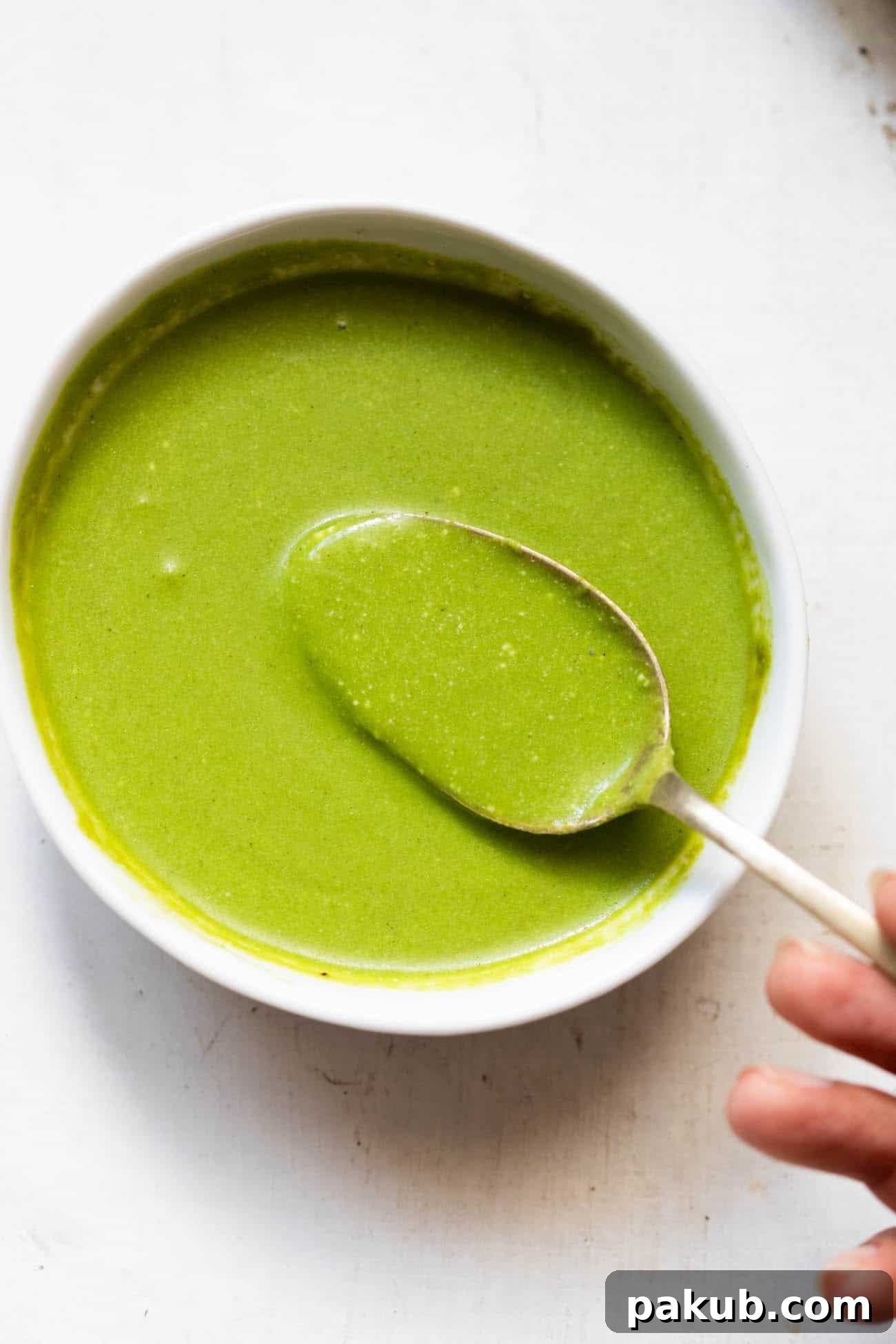A vibrant bowl of fresh homemade mint chutney with a spoon, ready to be served with Indian snacks.