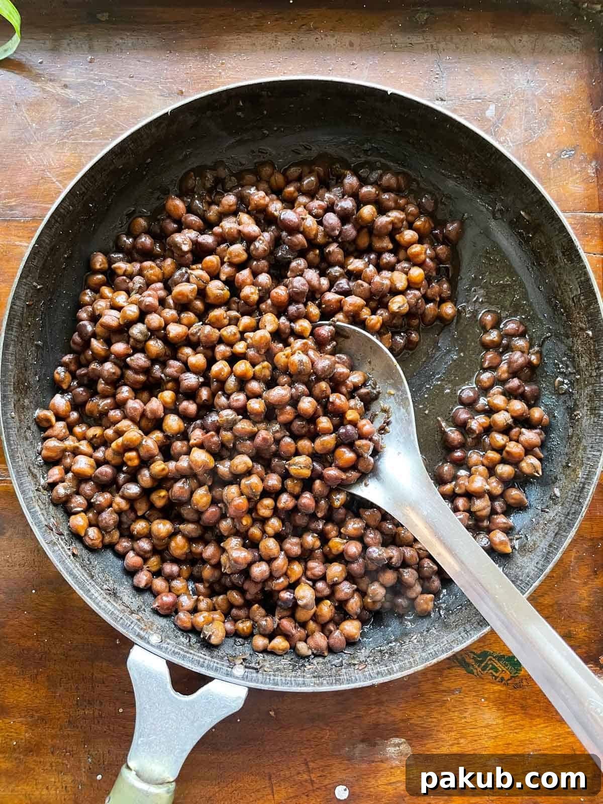 Flavorful Sookha Kala Chana, or dry black chickpeas, cooked and presented in an iron pan, ready to be served during festive celebrations like Navratri.