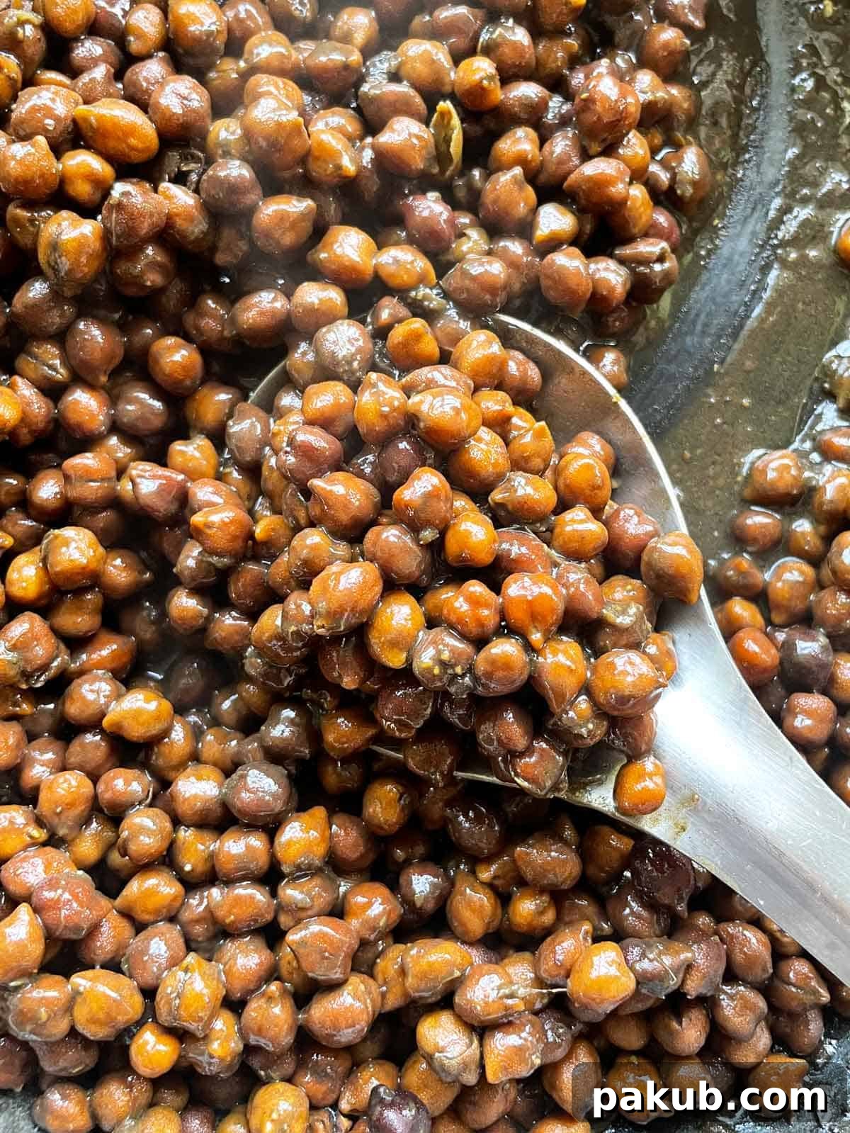 A close-up view of perfectly cooked Sookha Kala Chana, showcasing the tender black chickpeas coated in rich, dark spices, hinting at their deep flavor.