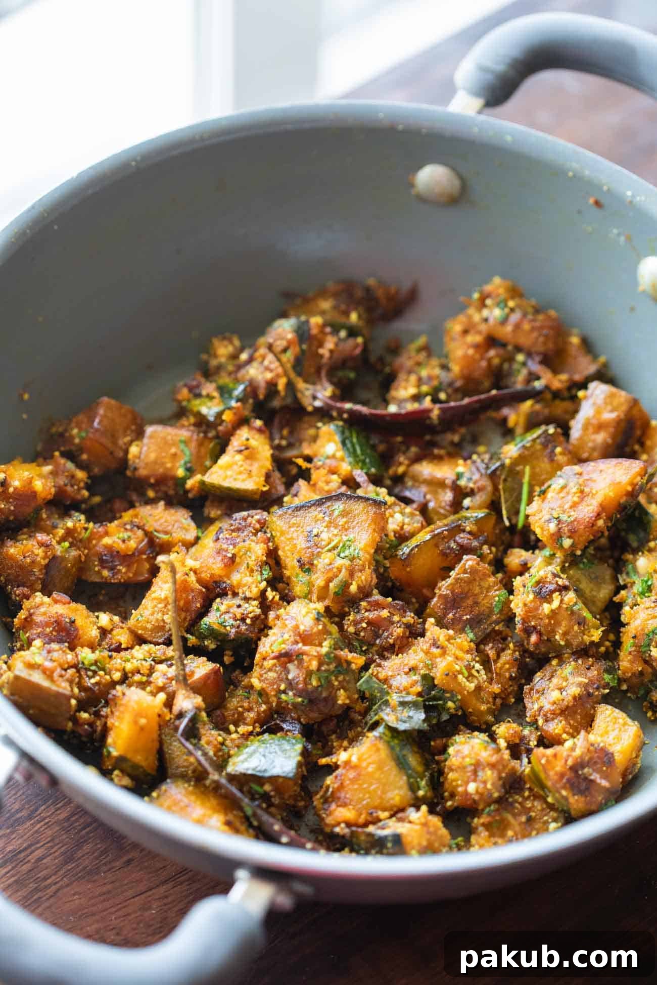 Peanut Pumpkin Sabzi served in a grey kadai, garnished generously with fresh coriander leaves.