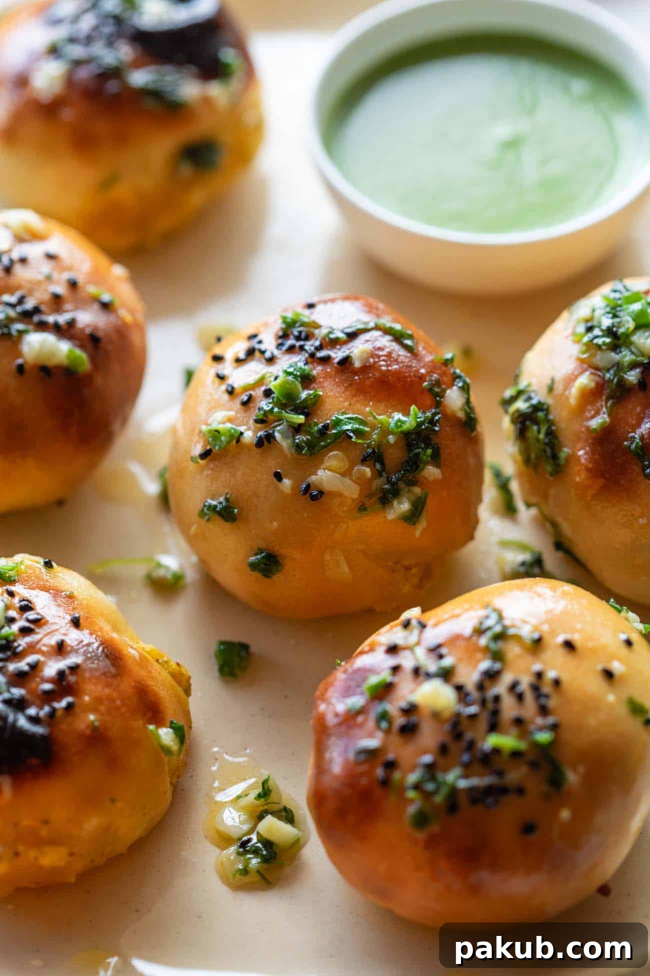 Tangy Achari Paneer Naan Poppers 4 A close-up shot of an Achari Paneer Naan Bomb with a creamy mint chutney in the background, showcasing its golden crust and inviting texture.