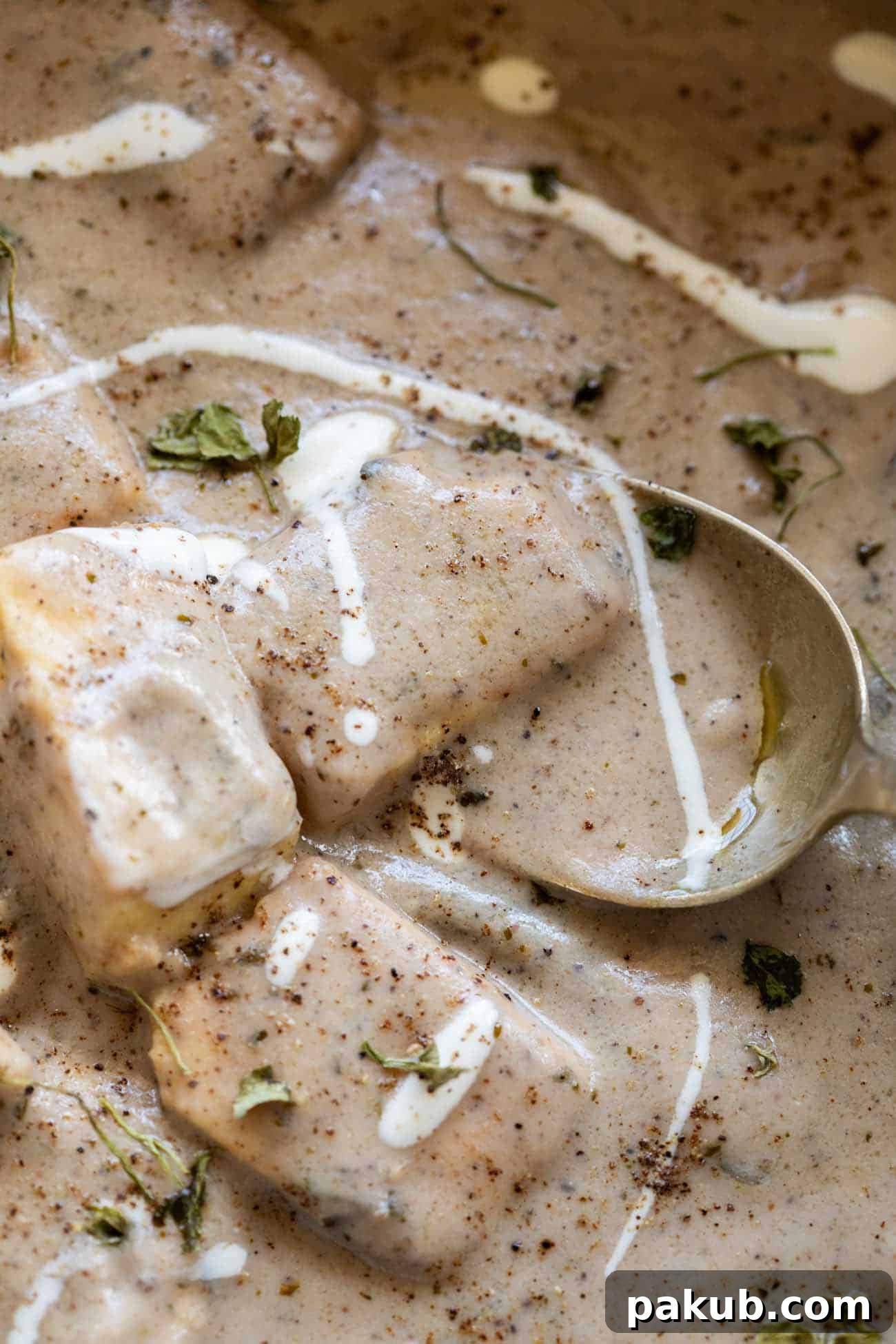 Bold Black Pepper Paneer 2 close up shot of paneer kali mirch gravy served in a bowl with cream drizzled on top