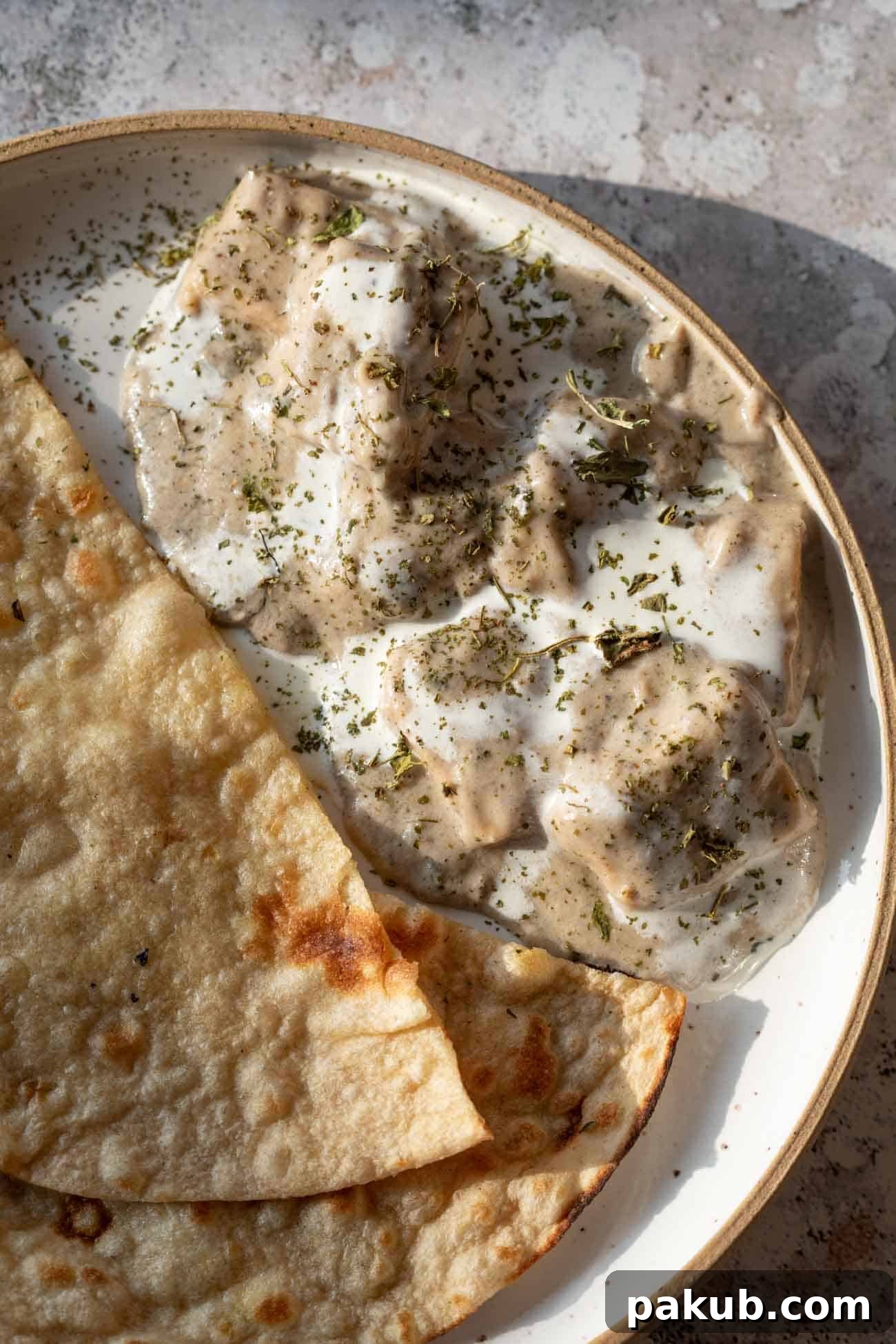 Bold Black Pepper Paneer 7 paneer kali mirch gravy served in a bowl with cream drizzled on top served with roti
