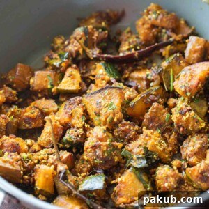 Rich peanut pumpkin sabzi served in a grey kadai, garnished with fresh coriander leaves, inviting a delightful vegetable side.