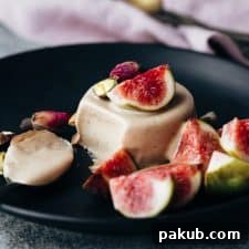 Elegant Masala Chai Panna Cotta served on a black plate, beautifully garnished with fresh figs, highlighting its creamy texture and sophisticated appeal.