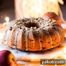 A beautifully baked Garam Masala Eggless Apple Bundt Cake, generously topped with a rich brown butter and rum glaze, promising a spiced and moist treat.