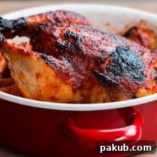 A perfectly cooked Indian Style Whole Masala Roast Chicken, glistening in a red Fujihoro casserole, showcasing its rich, spicy crust.