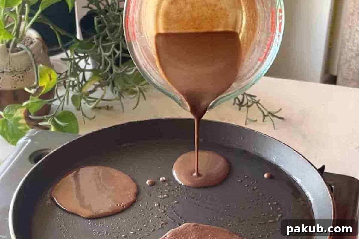 Step-by-step image demonstrating the pouring of pancake batter onto a hot, buttered pan, forming perfectly round pancakes.