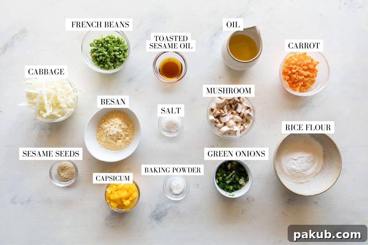 A vibrant collection of fresh ingredients for vegetable pancakes laid out on a clean surface, including rice flour, chickpea flour, sesame seeds, baking powder, thinly sliced cabbage, finely chopped carrots, French beans, mushrooms, bell peppers, green onions, salt, water, toasted sesame oil, and canola oil.