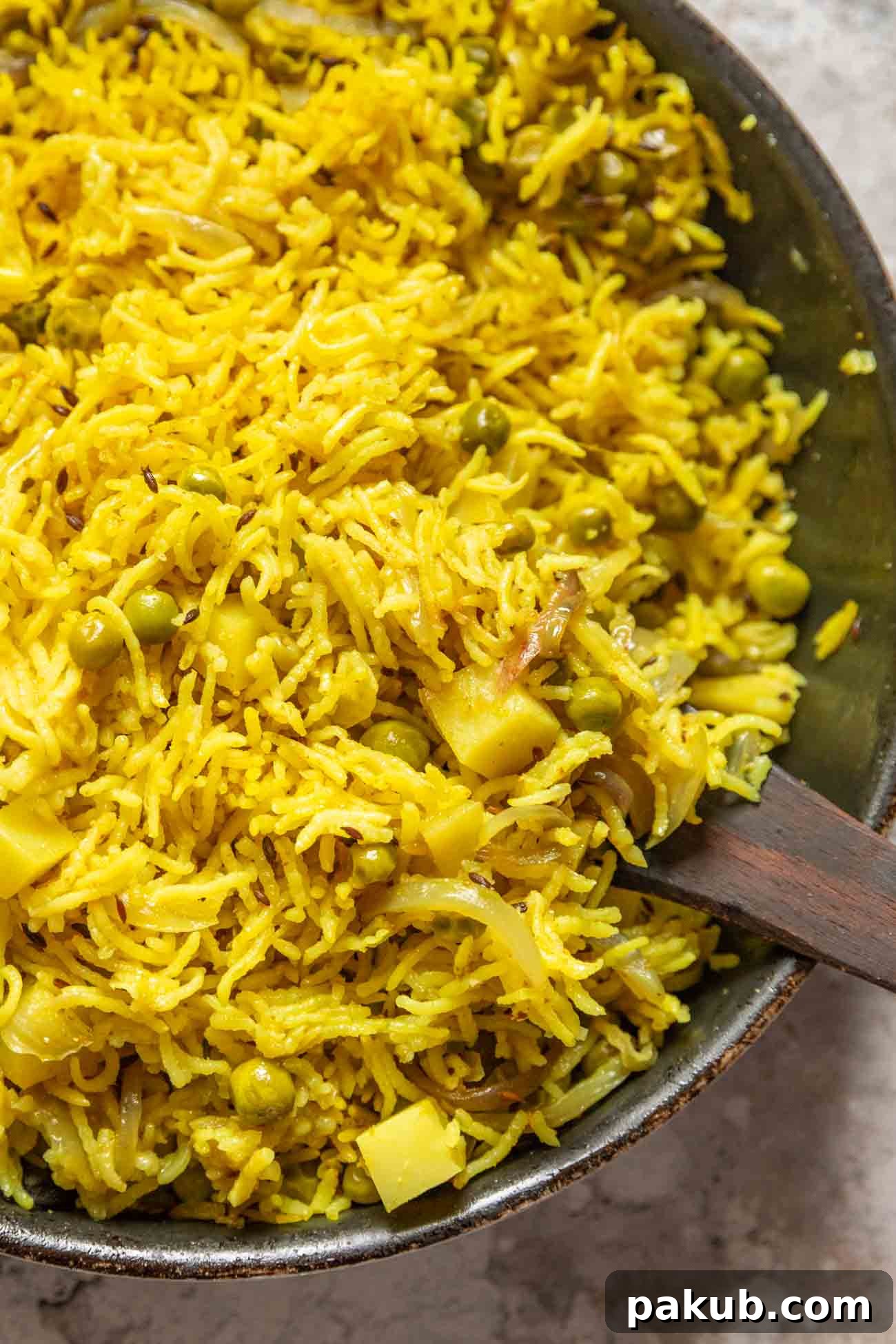 Tahari Tehri Uttar Pradesh's Golden Vegetable Pulao 6 A large pan filled with golden Tahari rice, garnished with fresh cilantro and a wooden spoon.