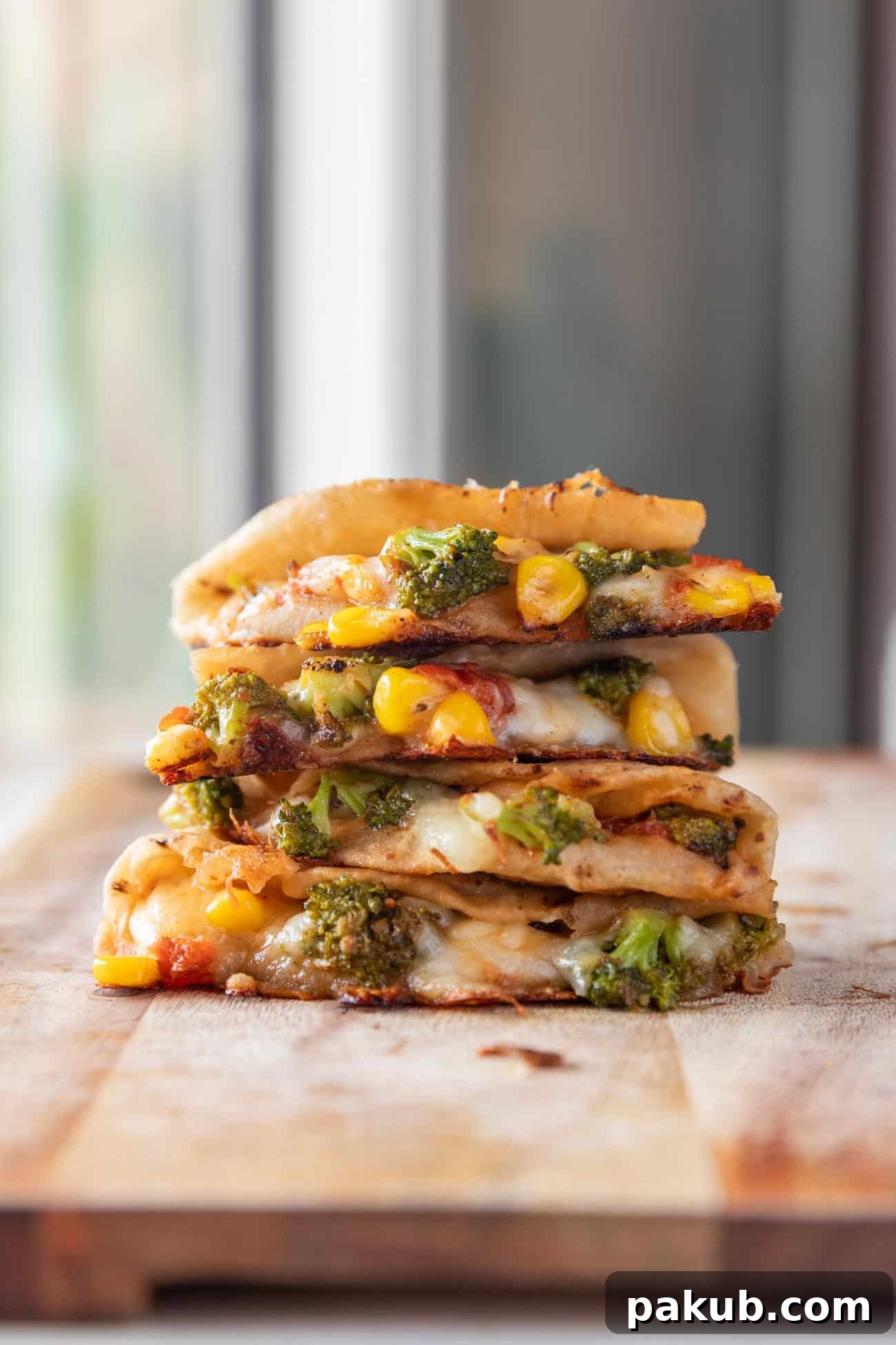 Golden Broccoli & Corn Quesadillas 2 A stack of golden-brown, cheesy broccoli corn quesadillas made with roti, garnished with fresh herbs.
