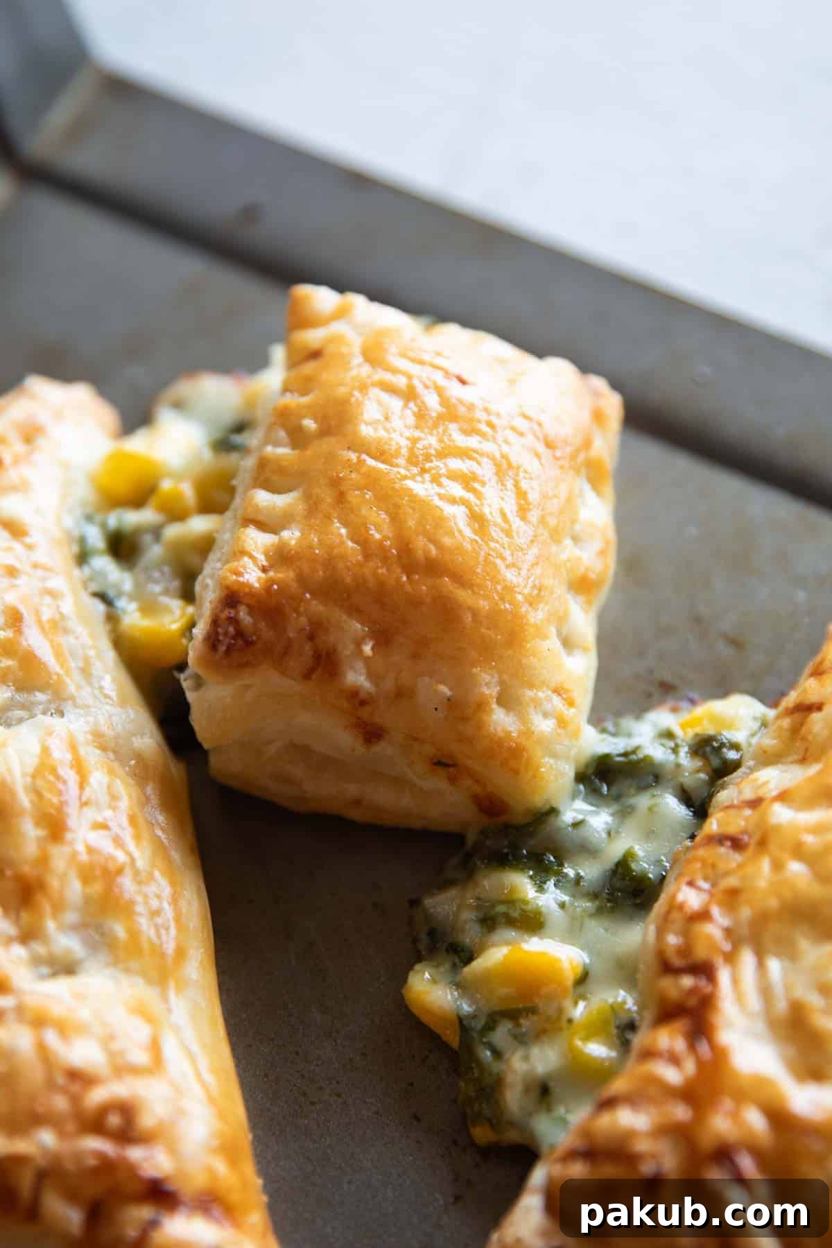 Golden-brown corn spinach puff, perfectly flaky, with a creamy filling visible