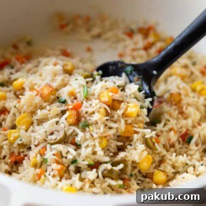 colourful rainbow rice in a white pan with a black rubber spatula