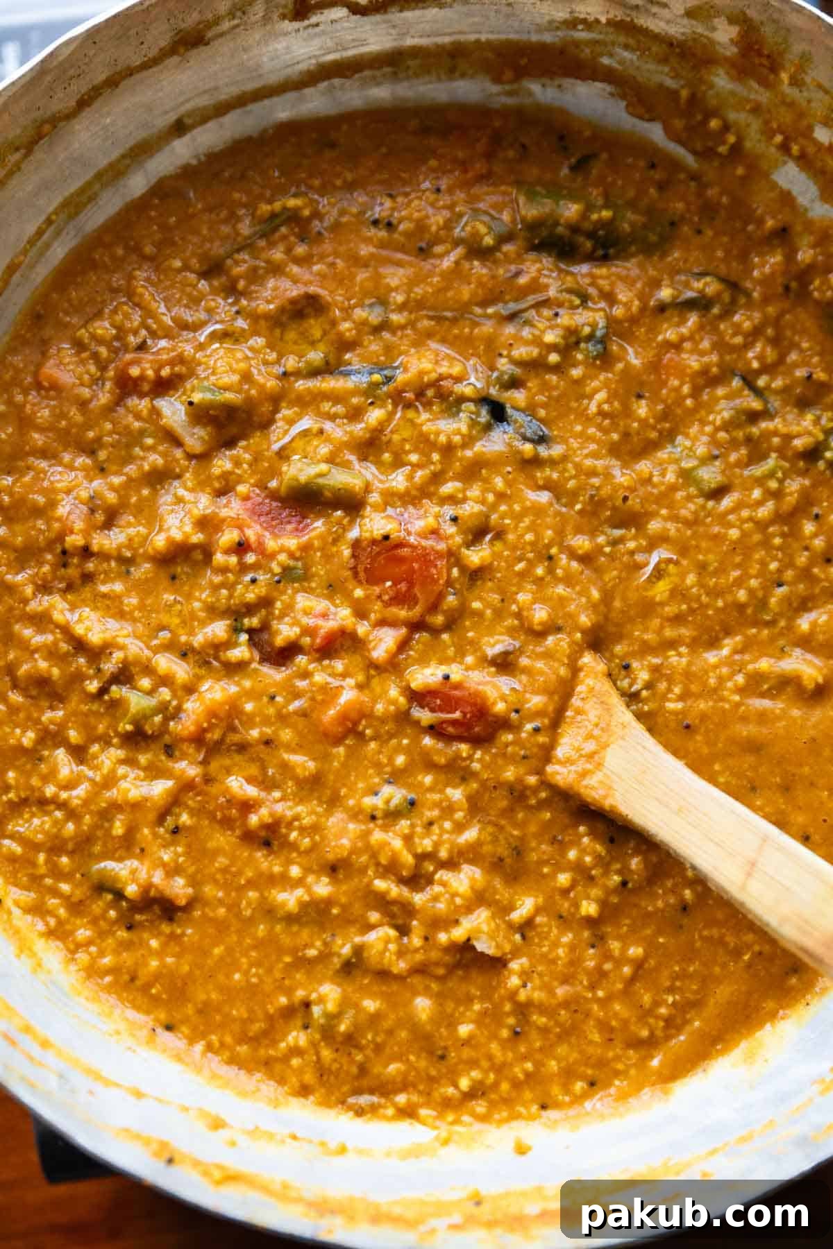 People and Such a Bath 6 A close-up shot of a richly textured Millet Bisi Bele Bath in a traditional kadai, with a wooden spoon, ready to be served.