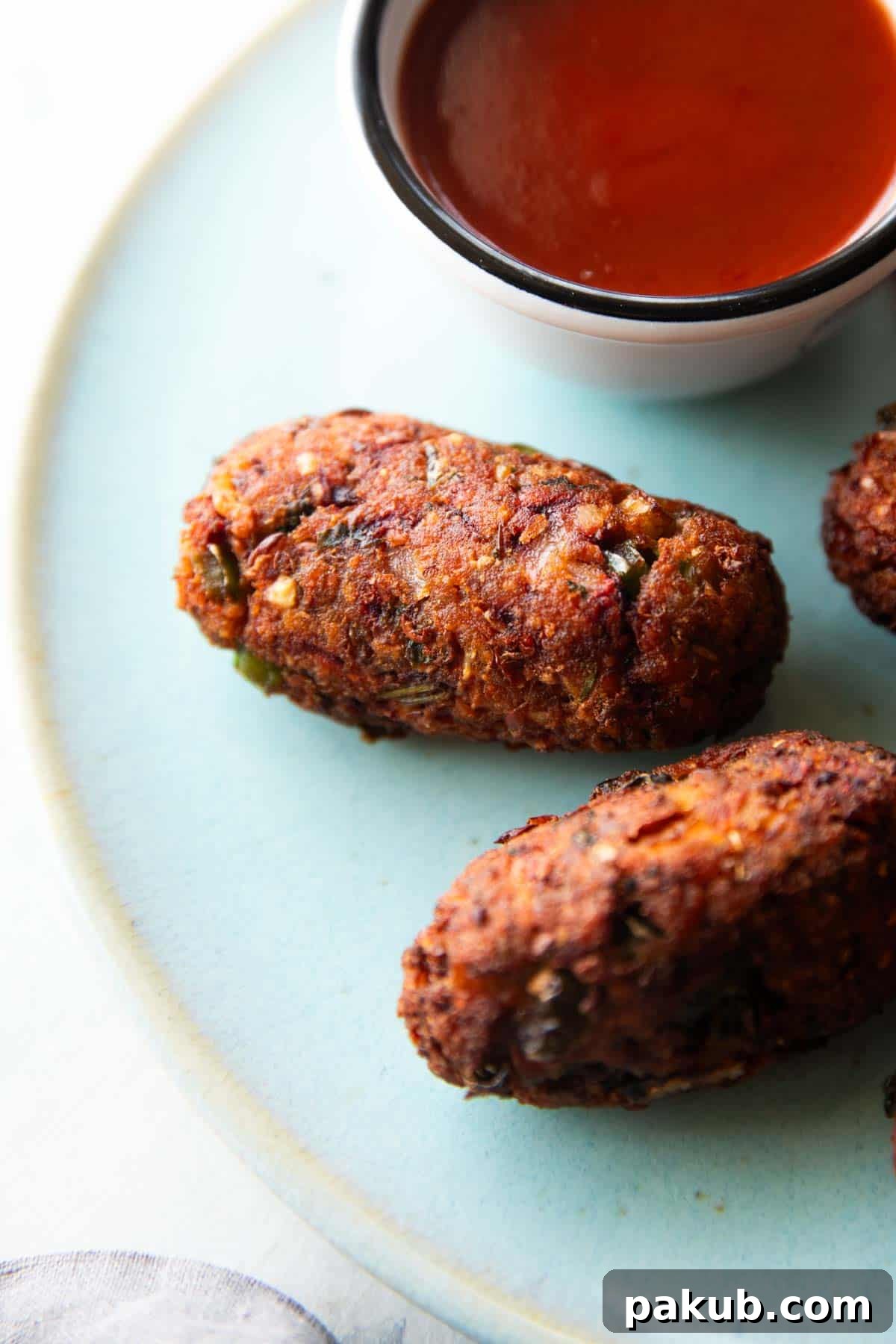 A tantalizing close-up shot of golden-brown sprouts cutlets arranged on a vibrant blue plate, with a dollop of bright red ketchup on the side, ready to be enjoyed.