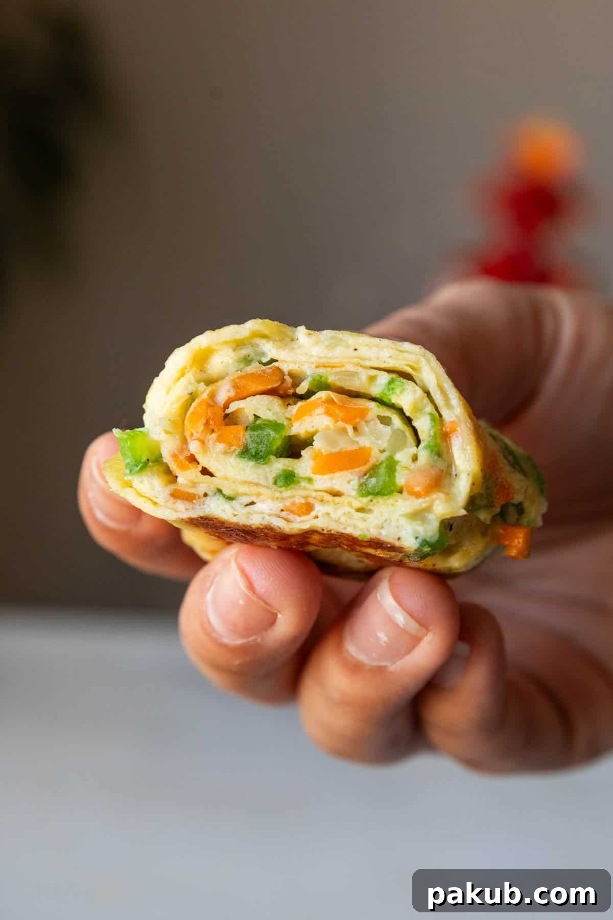 Fluffy Korean Egg Rolls 2 A close-up shot of perfectly rolled Korean Omelette Rolls held in a hand, showcasing their vibrant layers.
