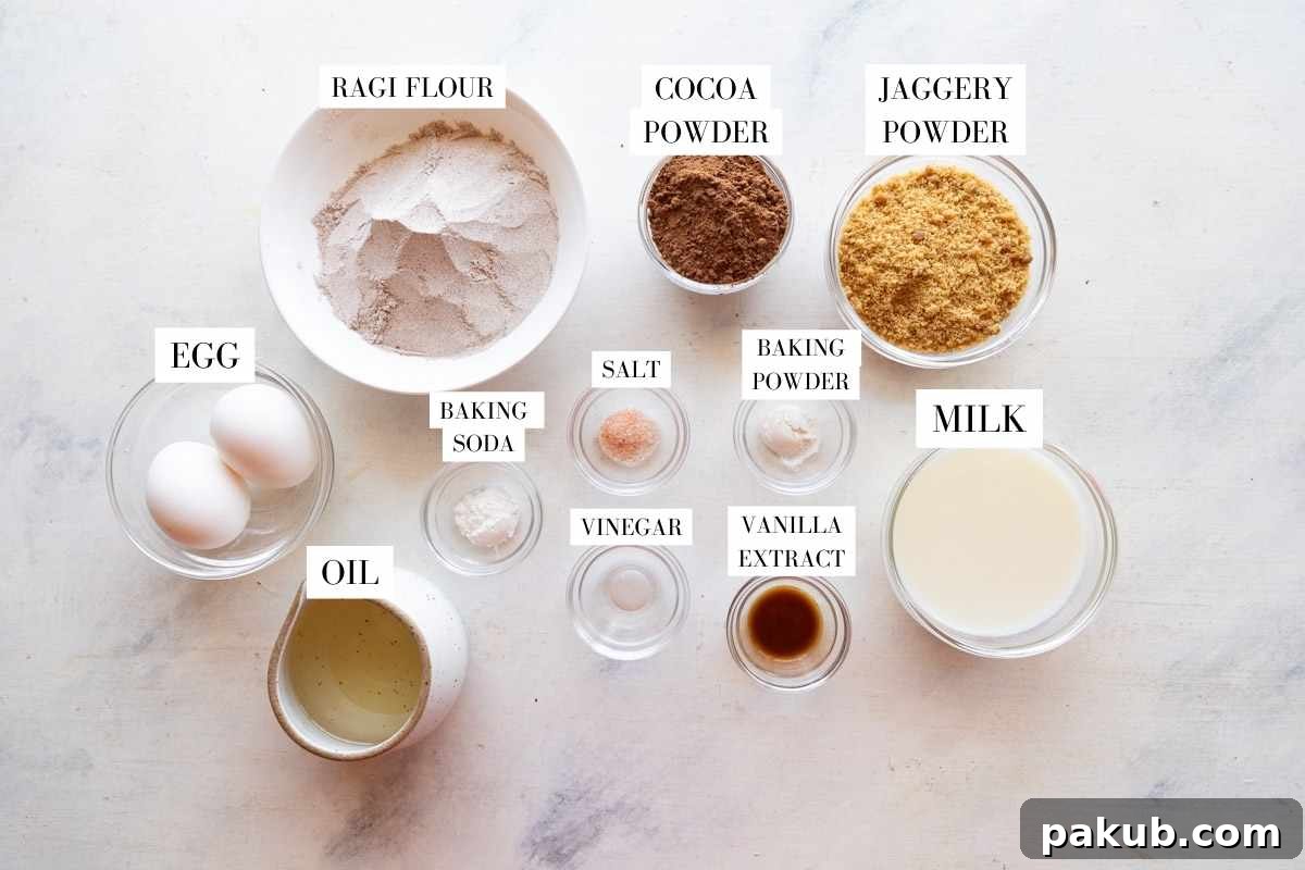 Wholesome Chocolate Ragi Indulgence 3 A selection of raw ingredients laid out on a wooden surface, including ragi flour, cocoa powder, eggs, jaggery, and oil, ready for baking.