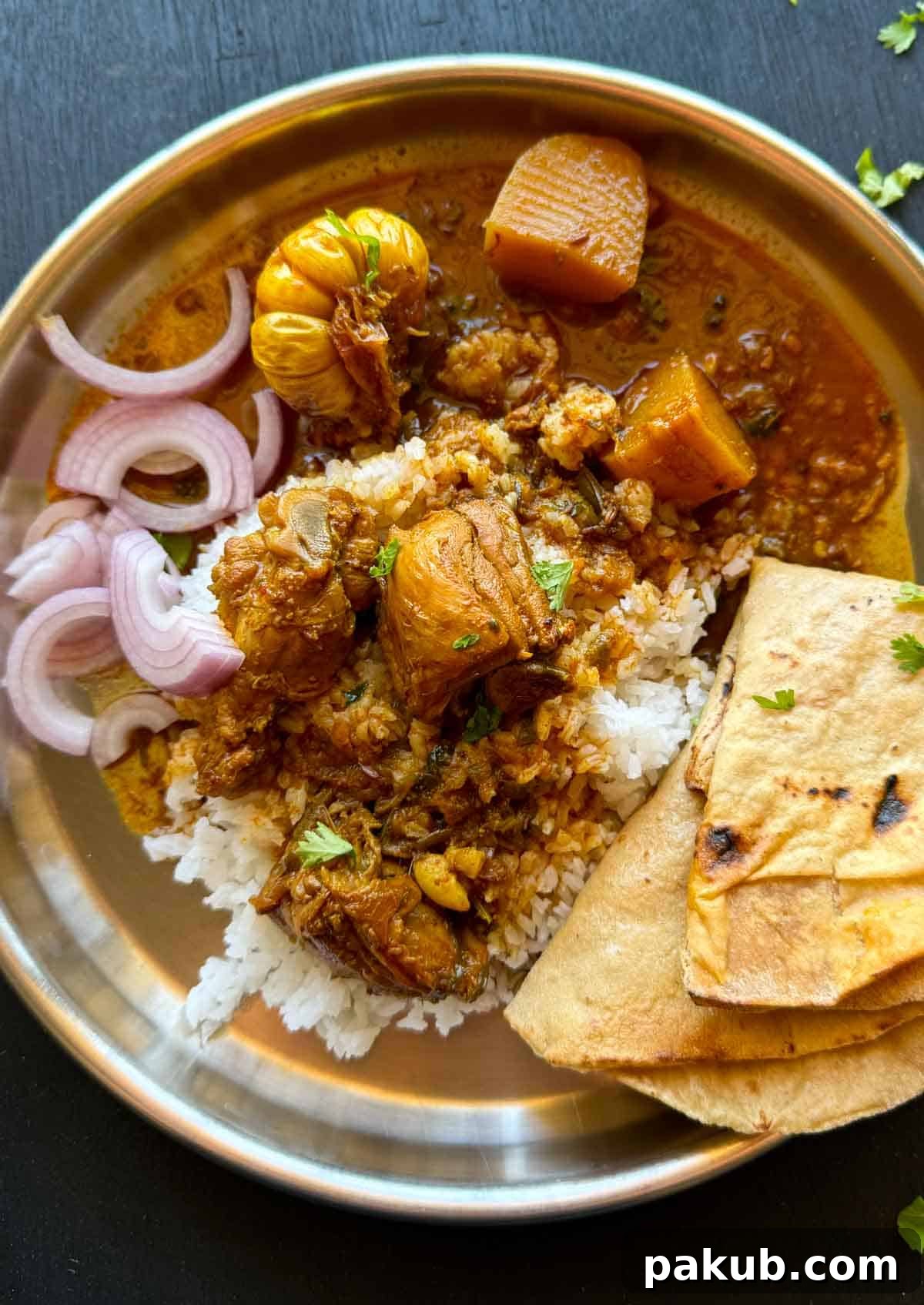 Bihari Chicken Curry presented on a traditional Indian thali, served alongside fluffy basmati rice, warm rotis, and a garnish of fresh onions and lemon wedges, showcasing a typical Bihari meal.